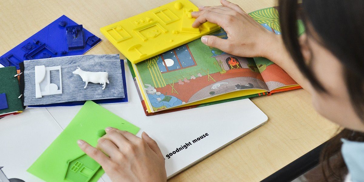Criança lendo um livro tátil graças à acessebilidade na impressão 3D