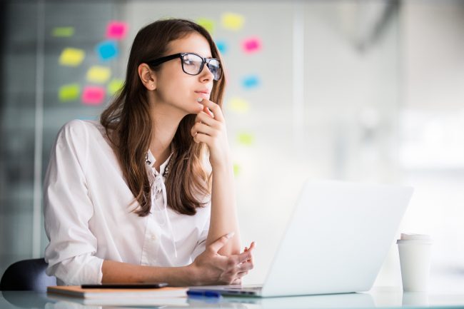 successful businesswoman working on laptop computer and thinks on new ideas in her office dressed up in white clothes